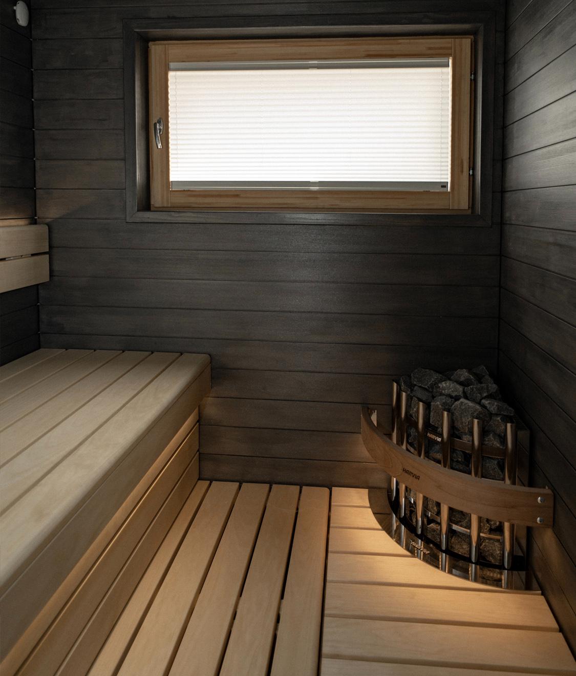 Sauna, jossa tummat seinäpaneelit ja lauteisiin upotettu kiuas.